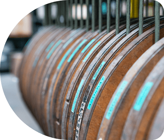 A row of wooden barrels with blue labels lined up in a storage area.