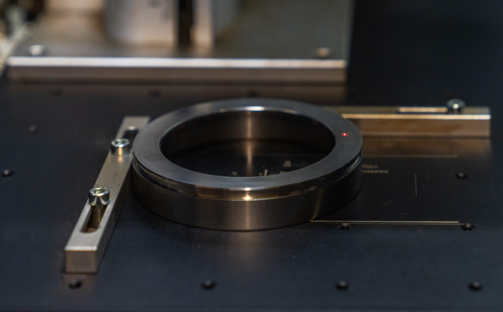 Close-up of a metal ring part on a machine bed in an industrial manufacturing setting.